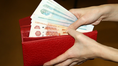 человек, держащий красный кошелек с деньгами